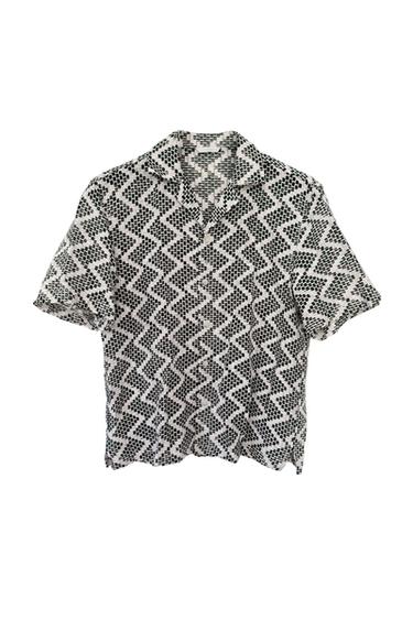 Short-sleeved shirt with geometric black and white print, white background.