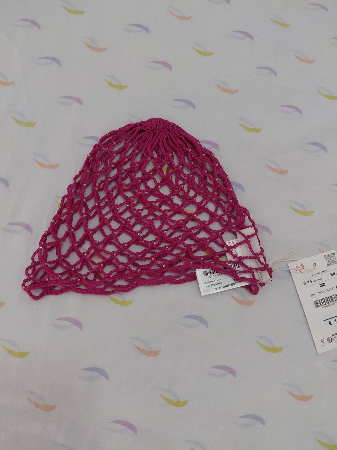 Fuchsia net hat with beads over fabric with half-moons. Text: INDITEX group, 6-14 YEARS, ART.: 7243 / 594 / 671.