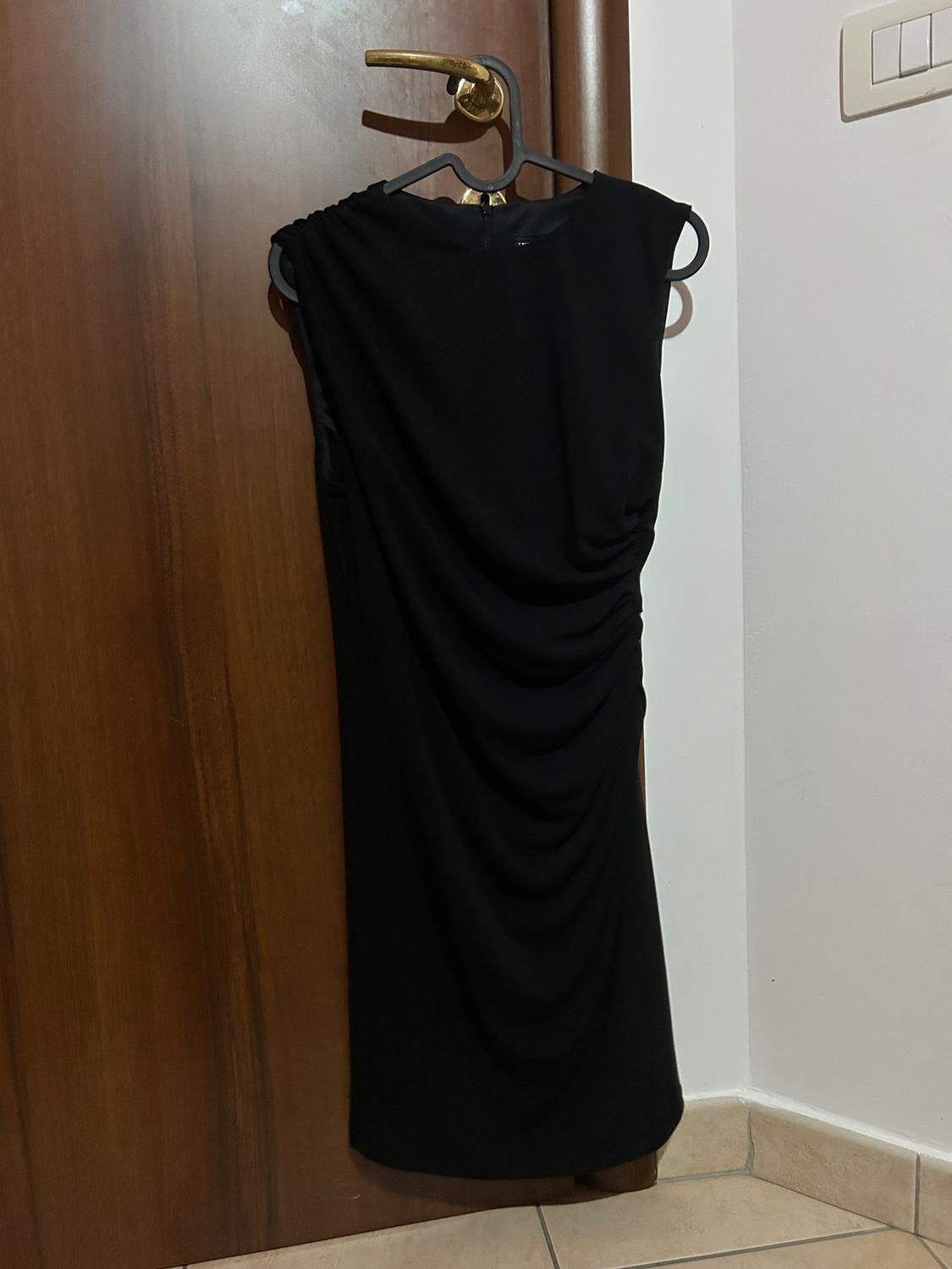 Front view of a black draped dress on a hanger.