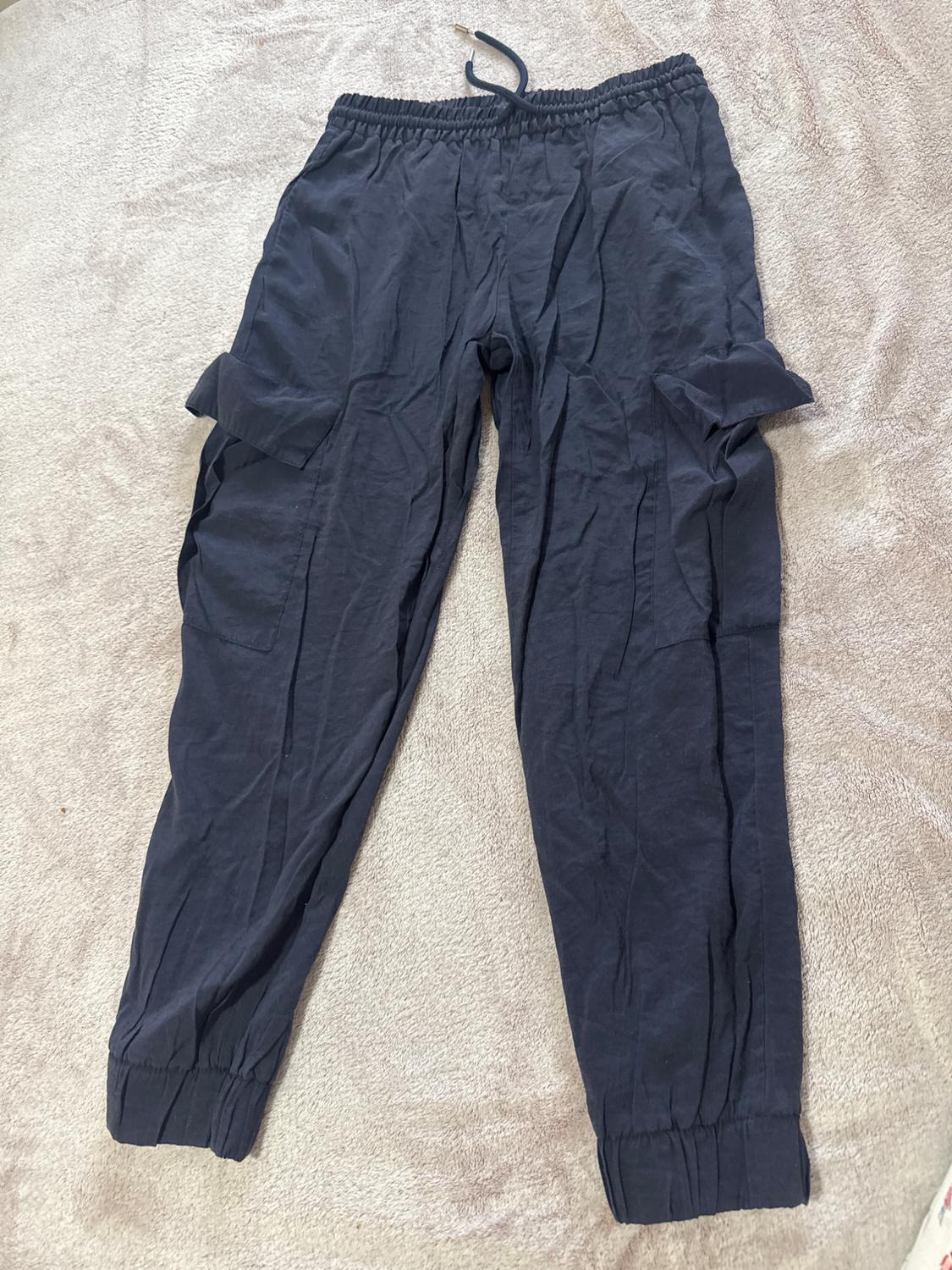 Navy blue cargo trousers with elasticated waist and cuffs, adjustable drawstring and side pockets, set against a light textured background.