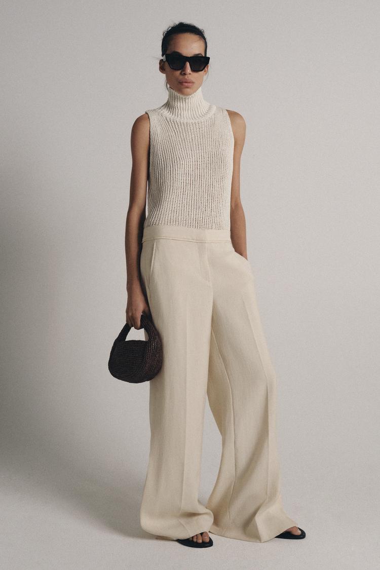 High-neck beige sleeveless top and cream wide-leg pants set with side pockets.