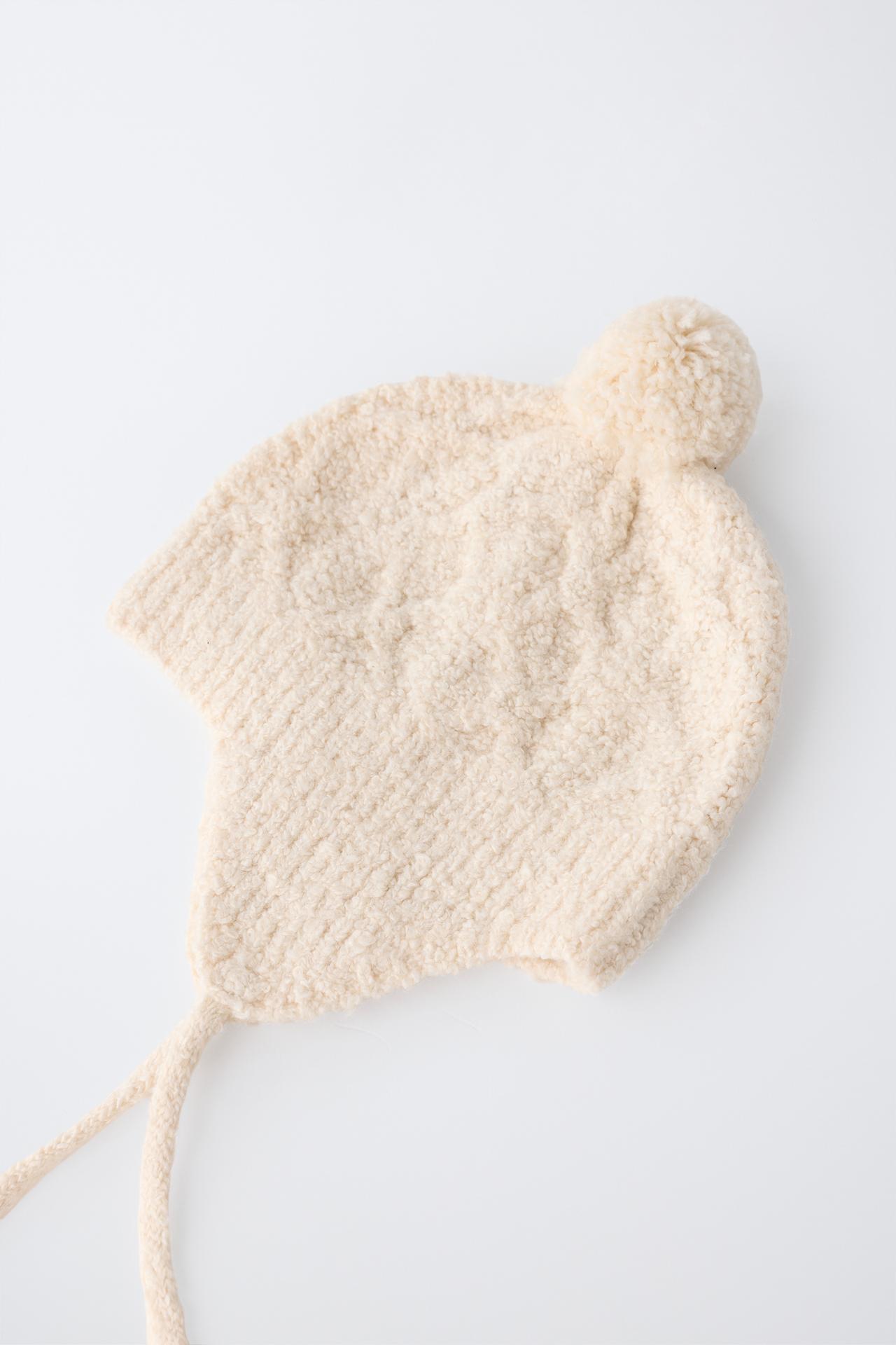 CABLE-KNIT POMPOM EARFLAP BEANIE — Ecru