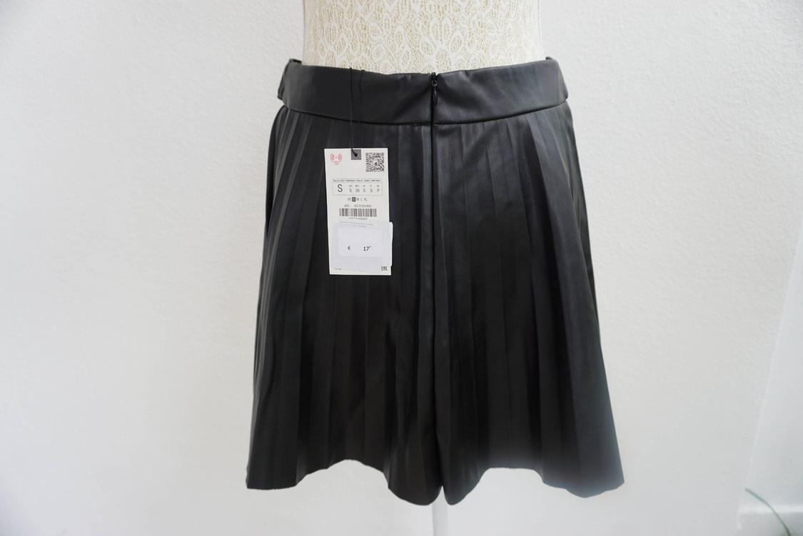 Black pleated skirt on a mannequin with a visible tag showing size S and price €17. White background.