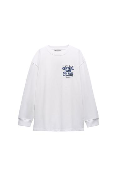 White long-sleeved T-shirt on a white background with text: New York CENTRAL PARK 5th AVE 625-17930*42 UPPER EAST SIDE NEW YORK. ZARA label.