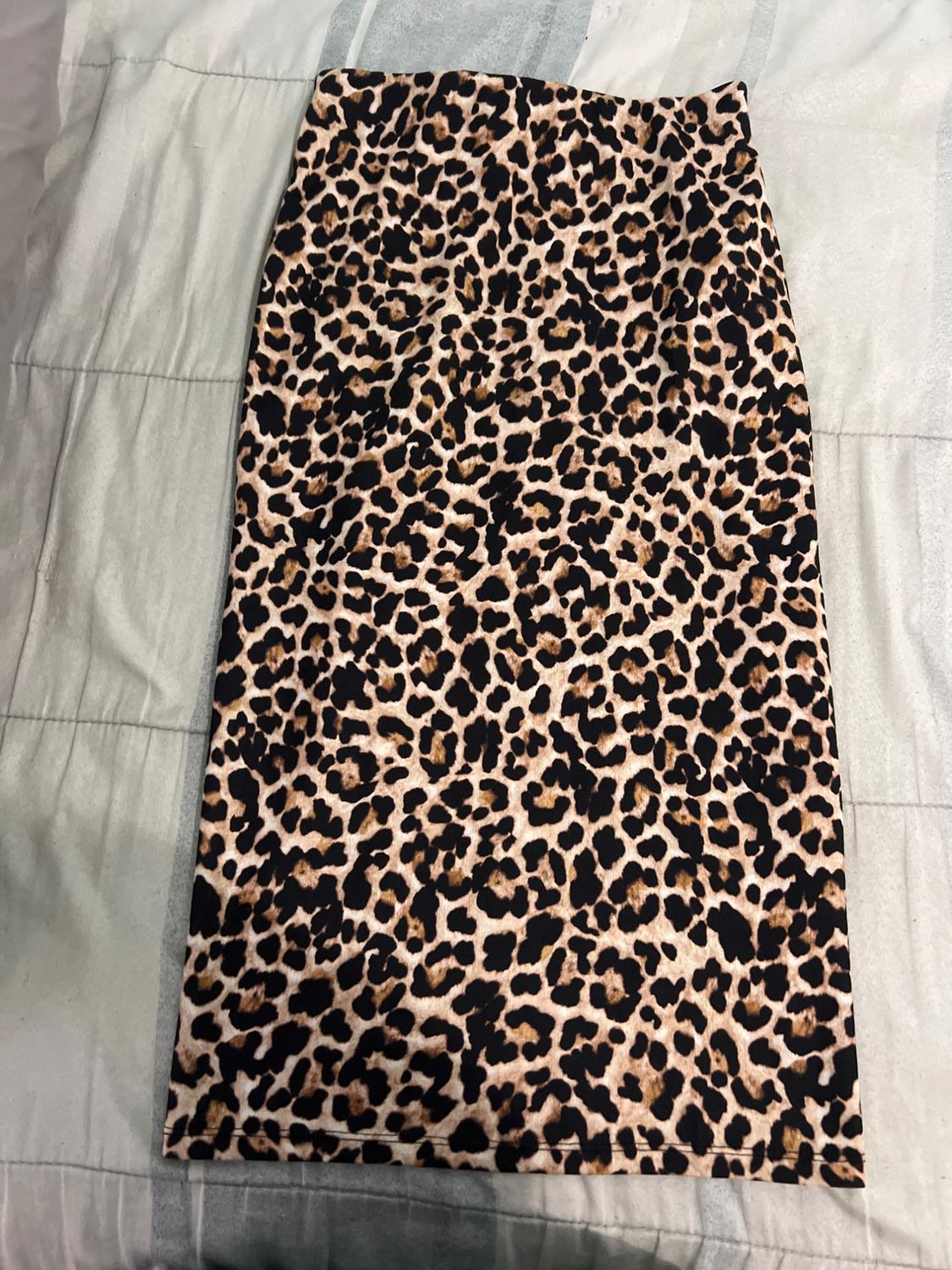 Leopard print pencil skirt in brown and black tones, on a bed with a white and grey duvet.