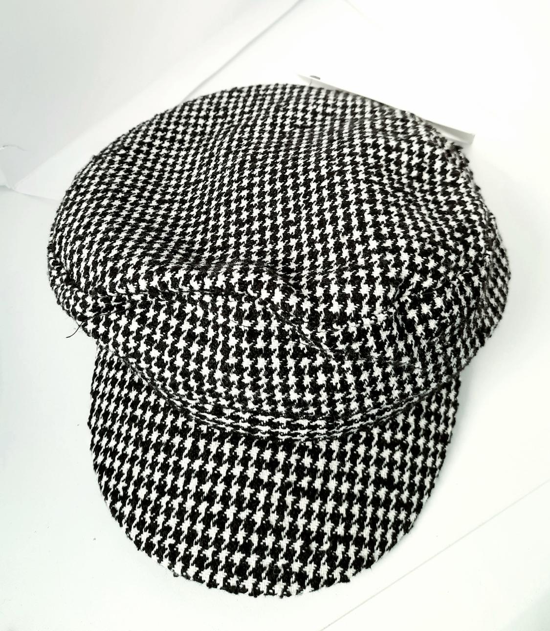 Black and white houndstooth pattern cap on a white background. Classic design with a brim and woven texture.