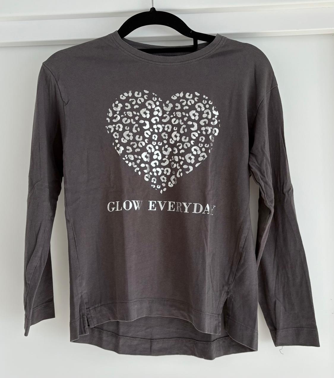 Grey long-sleeved T-shirt with an animal print heart and "GLOW EVERYDAY" text in white letters.