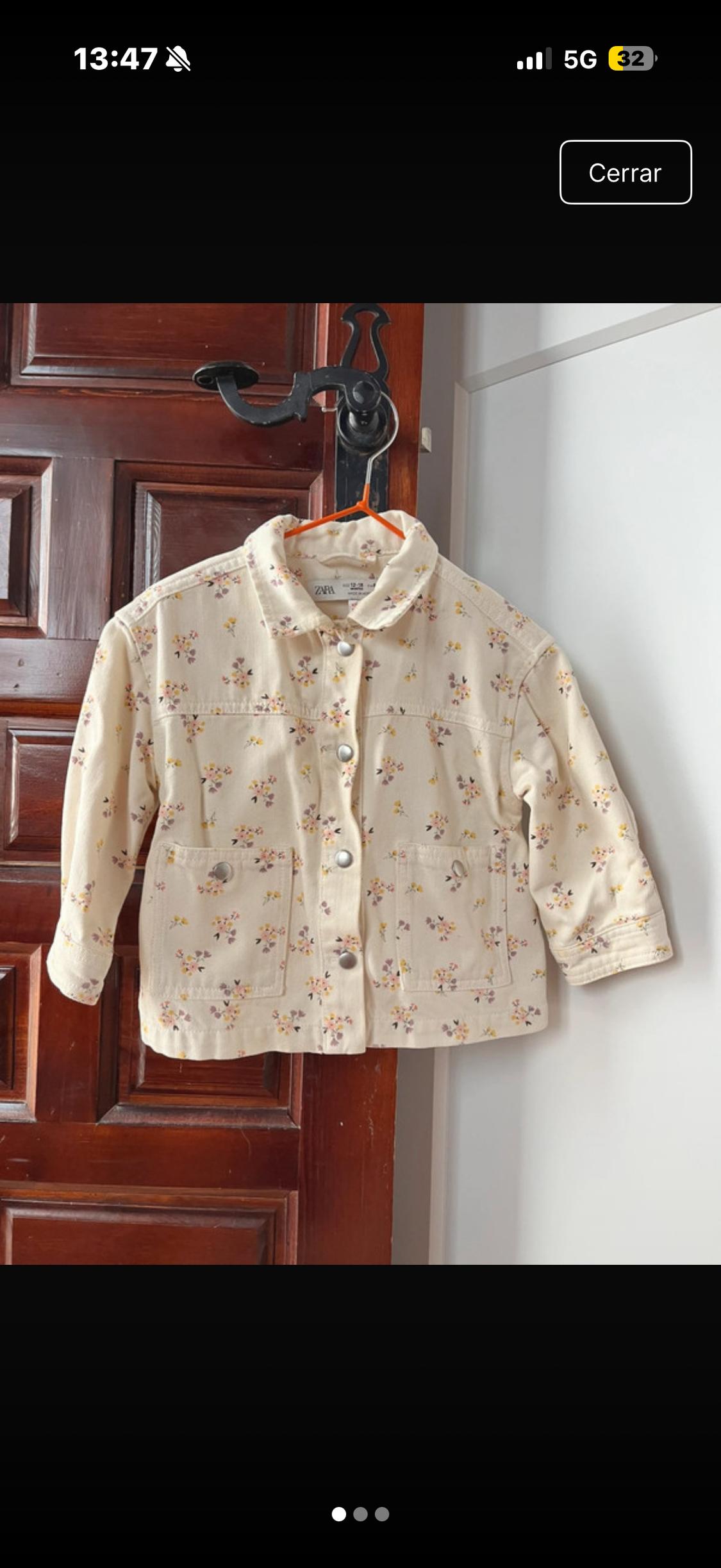 Beige children's jacket with a floral print hanging on a wooden door. Visible label: "ZARA 92 cm 1-2 years".