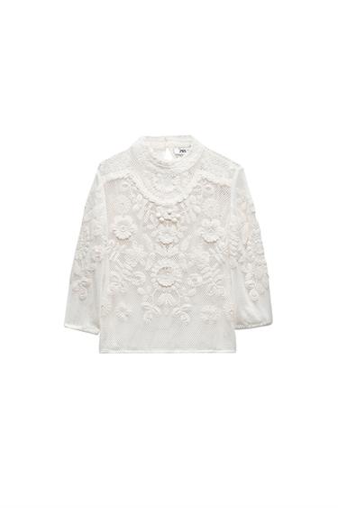 Front view of a white blouse with floral lace and long sleeves