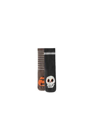 Two socks on a white background. One brown striped with a pumpkin, and the other black with stripes on the upper part and a skull.