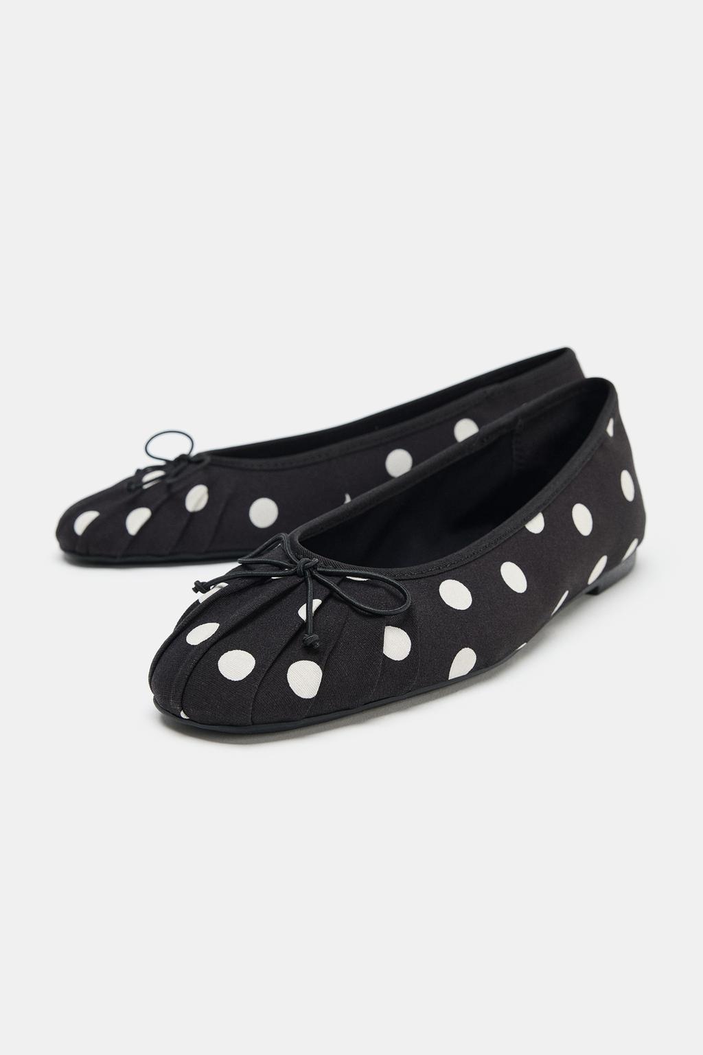 Black ballet flats with white polka dots and a decorative bow on the front.