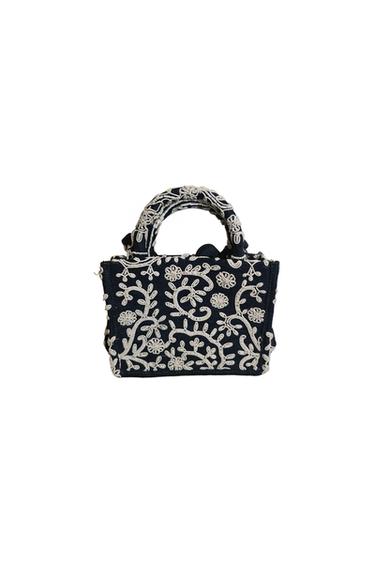 Small, dark blue handbag with white floral embroidery and short handles, on a white background.