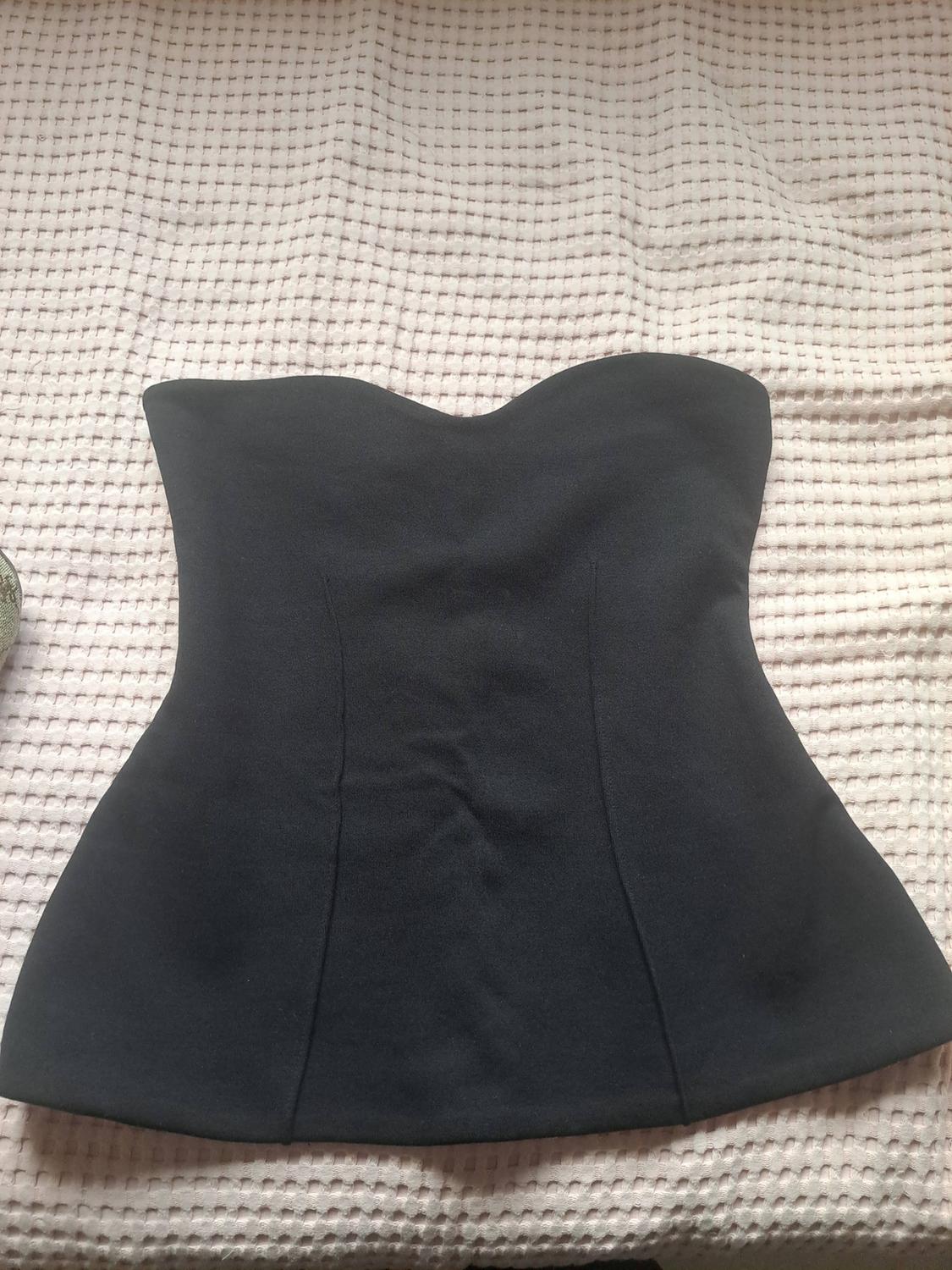 Black strapless top with a sweetheart neckline and vertical seams, shown on a light-coloured textured blanket.