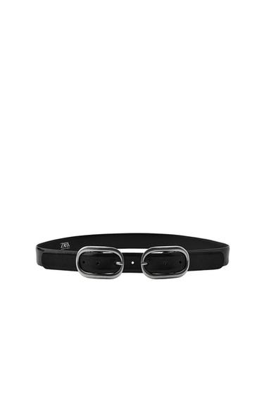 Front view of a black belt with a double oval metallic buckle. Visible text: "ZARA".