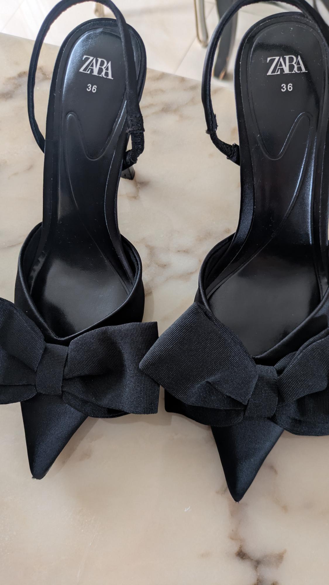 Black slingback high heels with a pointed toe and a front bow on a light marble floor. Visible text: ZARA 36.