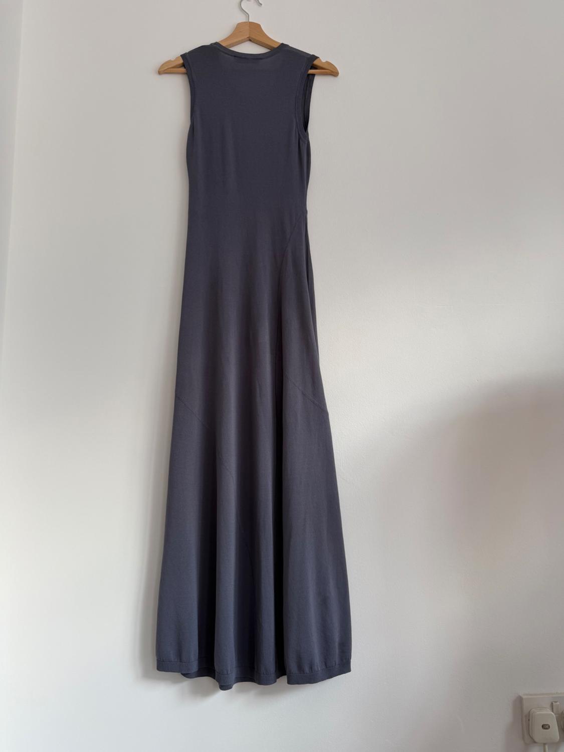 Sleeveless maxi dress in dark grey hanging on a wooden coat hanger against a white wall.