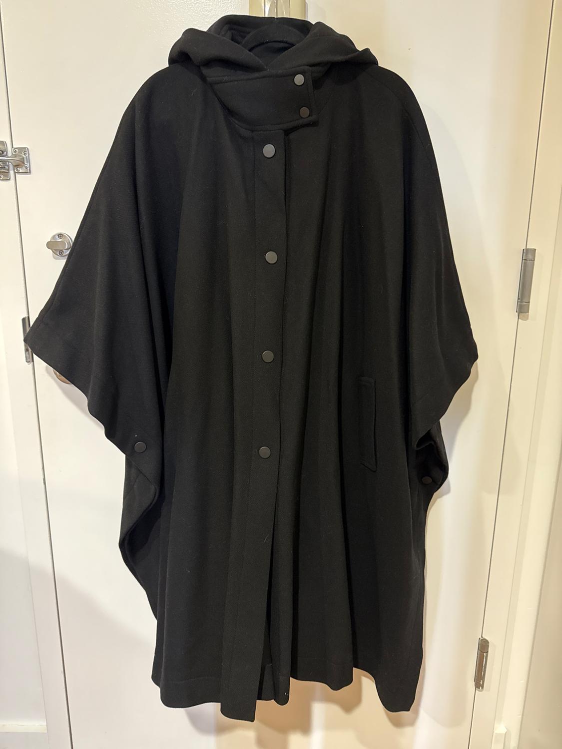 Black cape with hood and buttons, hanging on a white door.