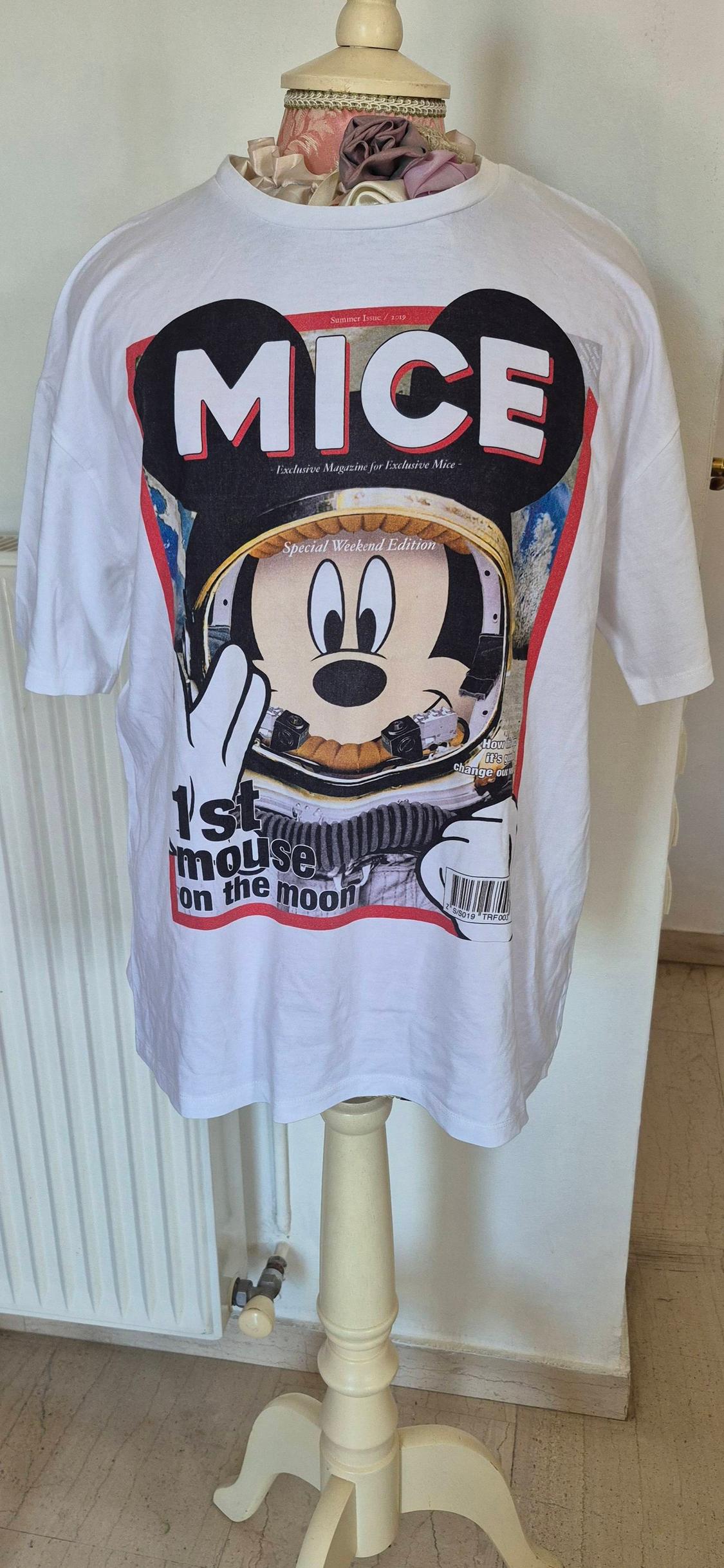 White T-shirt with astronaut mouse design and text: "MICE", "1st mouse on the moon". Displayed on a mannequin indoors.