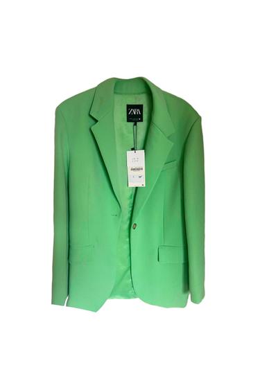 Green jacket hanging with visible Zara label. Text on label: "JOIN LIFE". White background.
