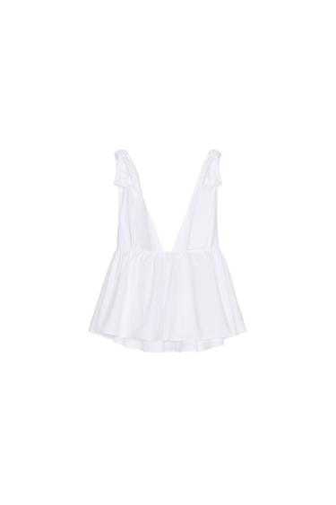 Back view of a sleeveless white blouse featuring a deep V-neck and ruffles.