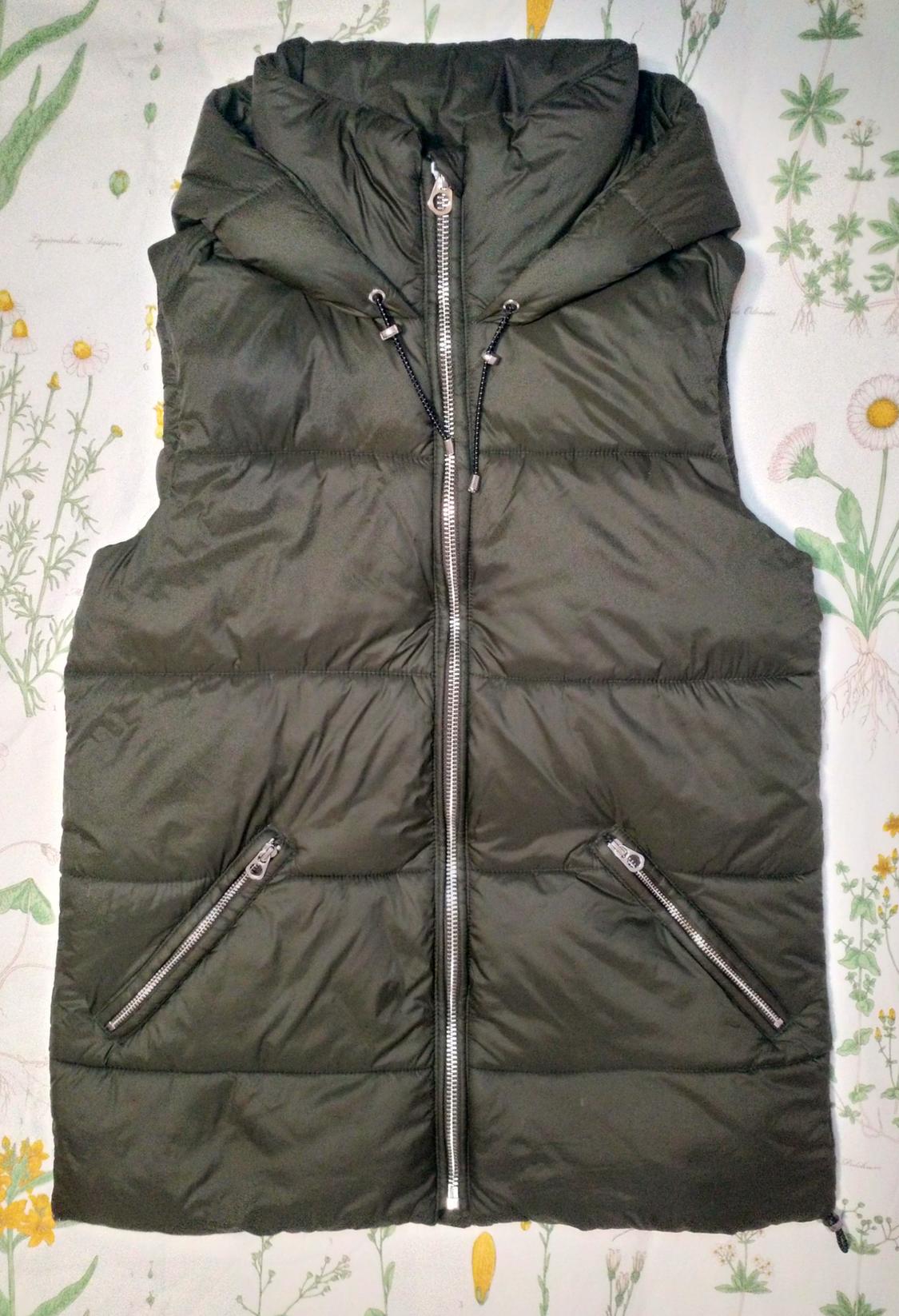 Front view of a dark green padded gilet with a hood and side zip pockets.