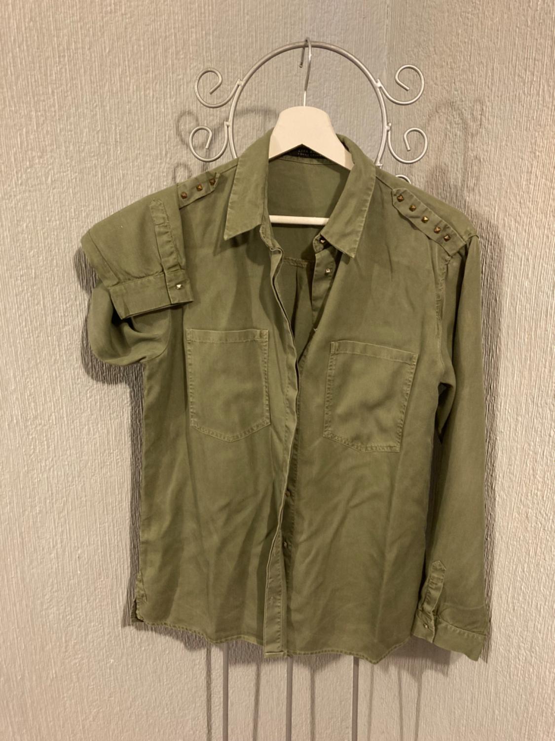 Front view of a green shirt with front pockets and button details on the shoulders.