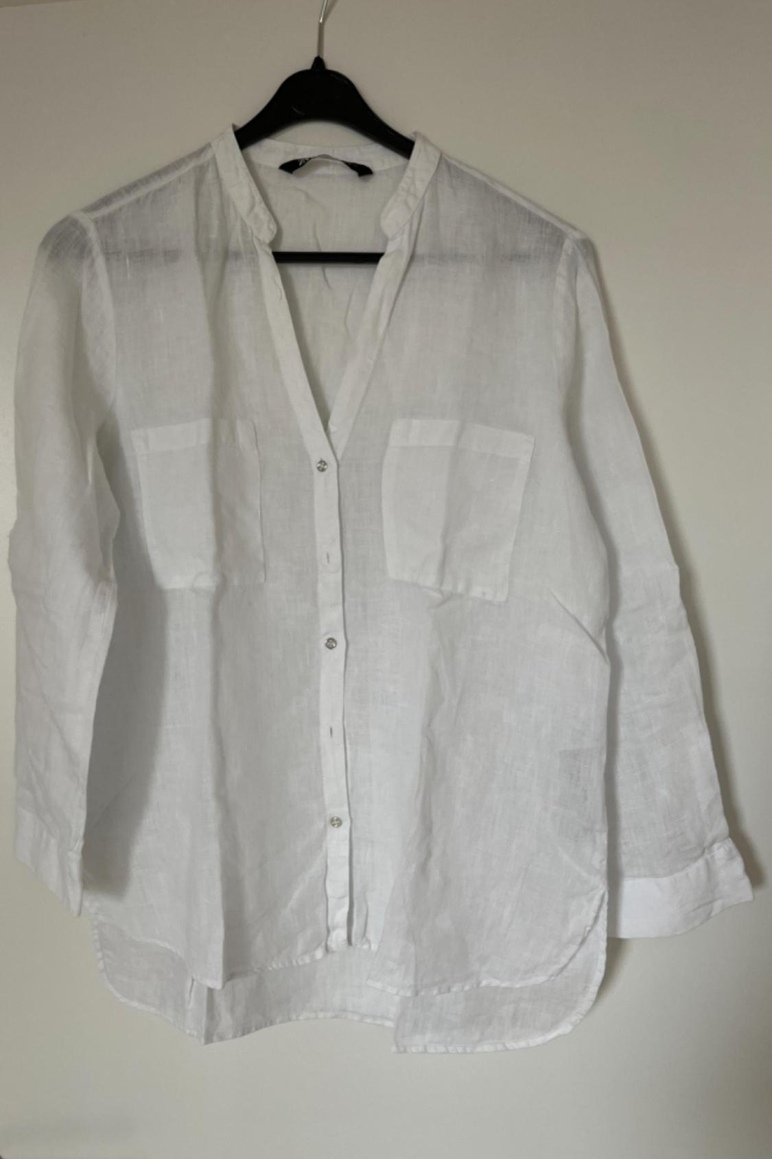 Front view of a white shirt with front pockets and buttons.