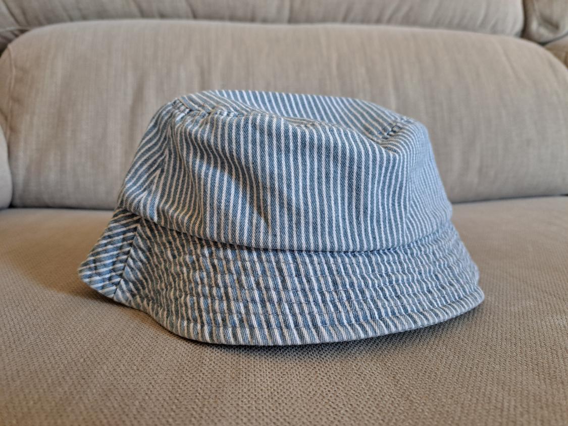 Blue and white striped fabric hat on a beige sofa. The design is casual and relaxed.