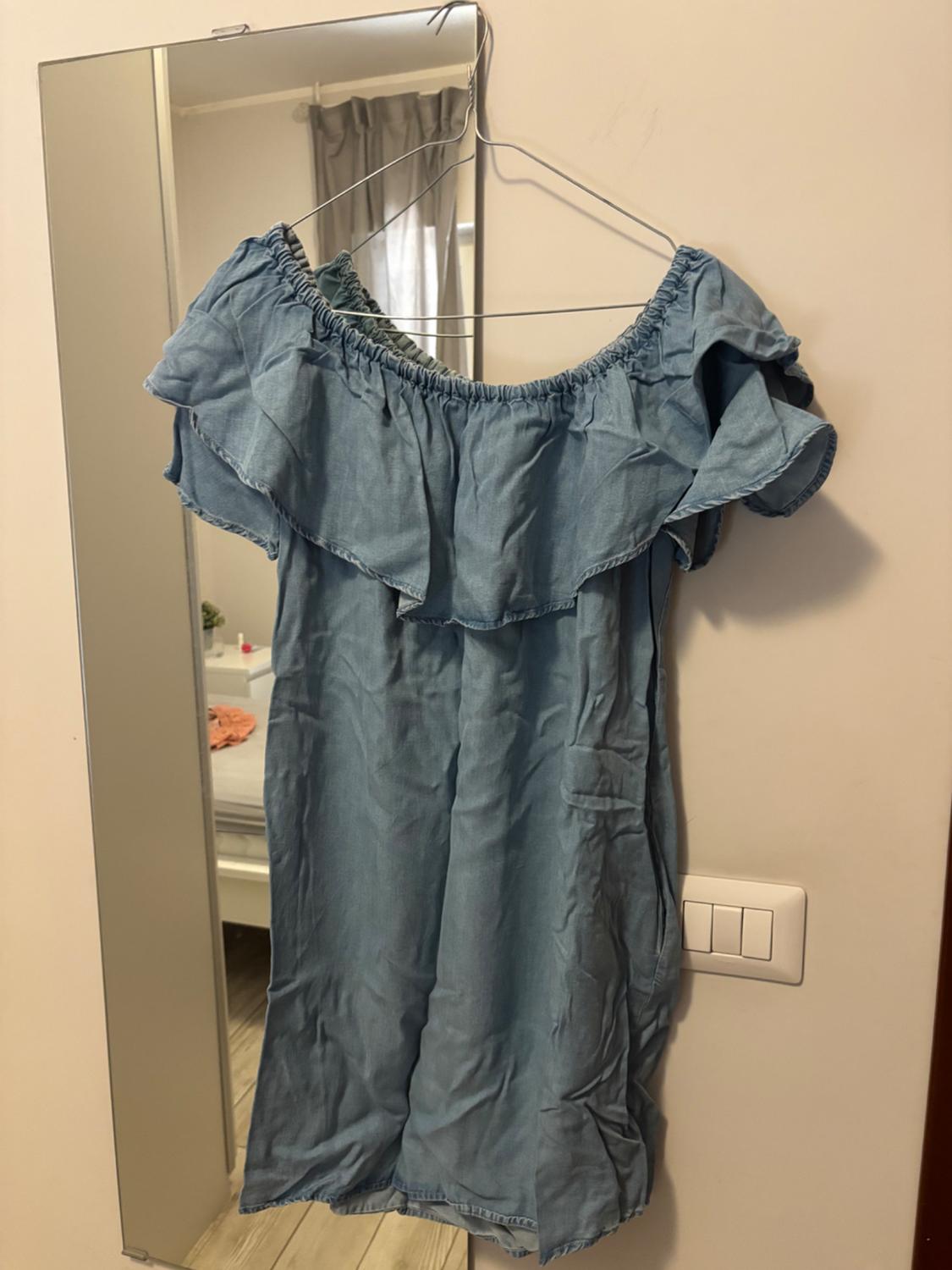 Light blue dress with off-the-shoulder sleeves and a ruffle, hanging on a clothes hanger over a mirror in a room.