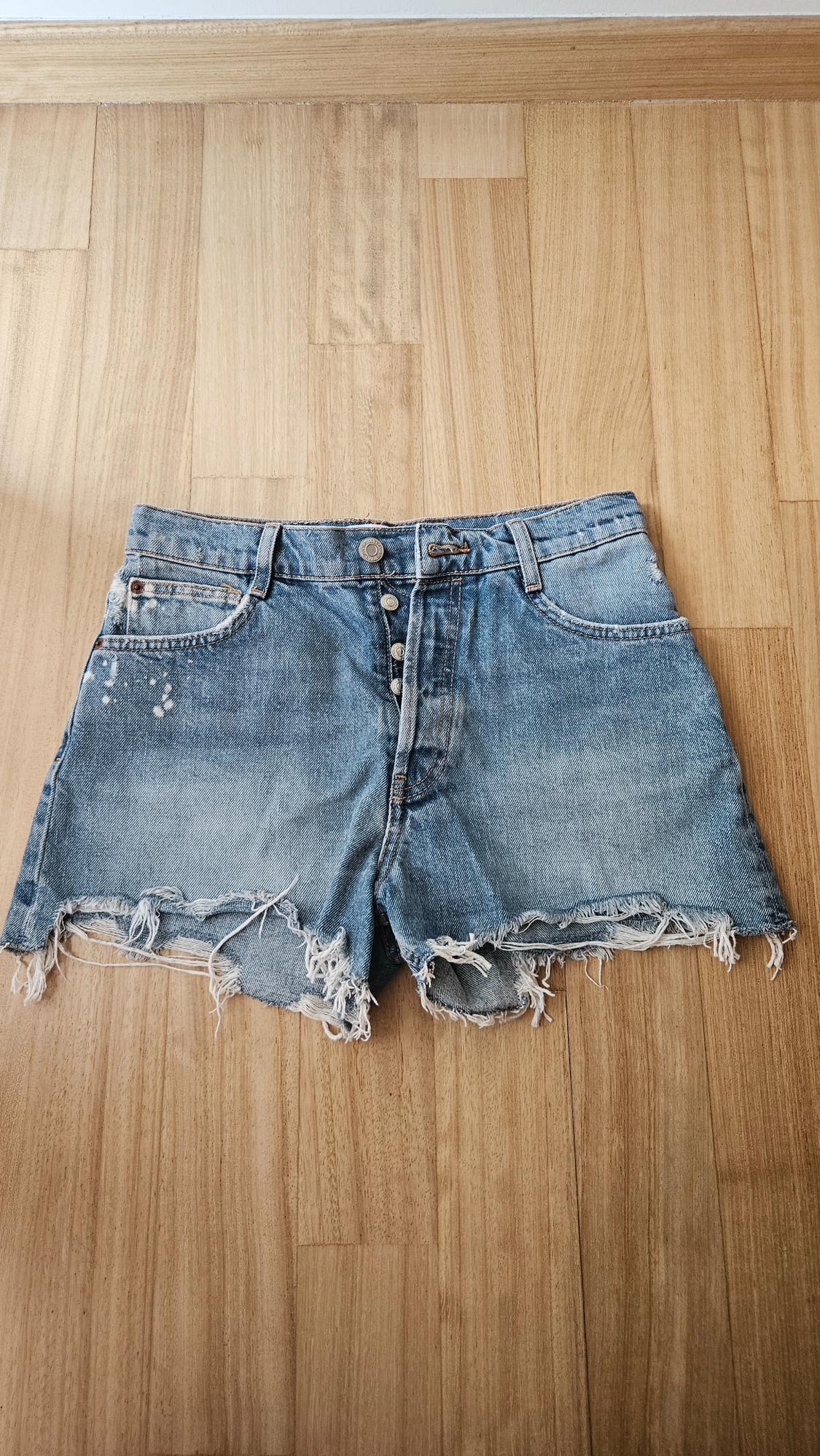 Front view of distressed denim shorts with visible buttons and front pockets.