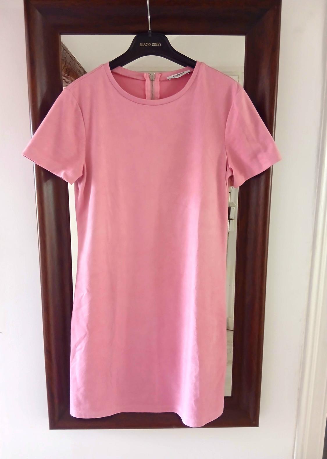 Pink short-sleeved dress hanging on a black hanger with a "BLACKY DRESS" label, reflected in a wooden-framed mirror.