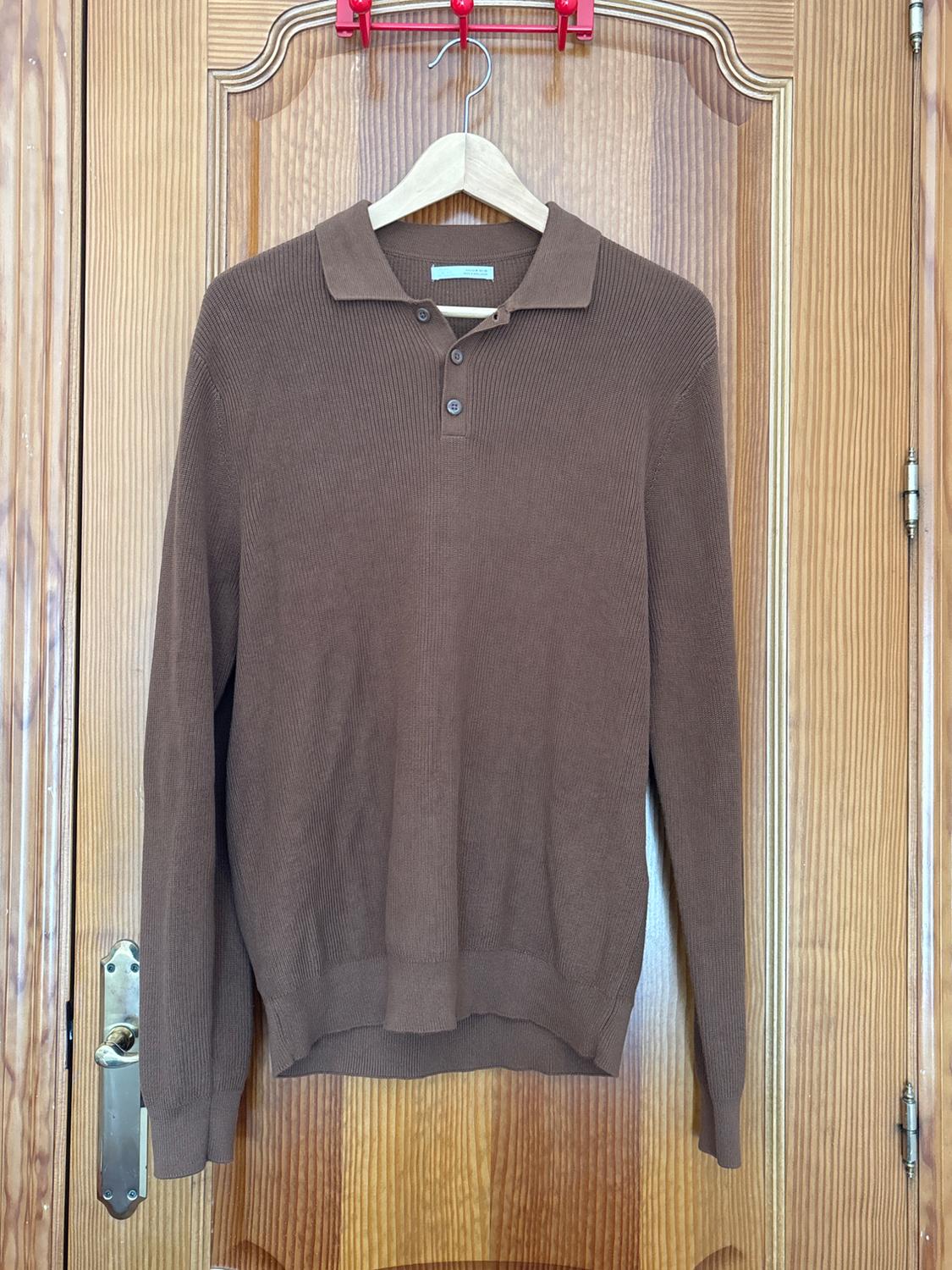 Brown long-sleeved polo neck jumper with three buttons, hanging on a wooden hanger over a wooden door.