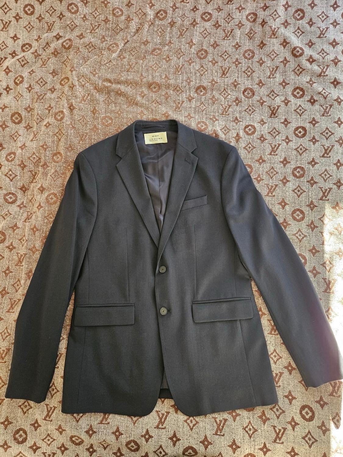 Dark Americana with two buttons and pockets with a flap, on a brown patterned fabric background.