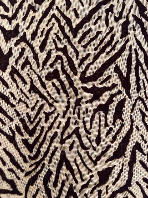 Fabric with black stripe print on a beige background, similar to an animal pattern.