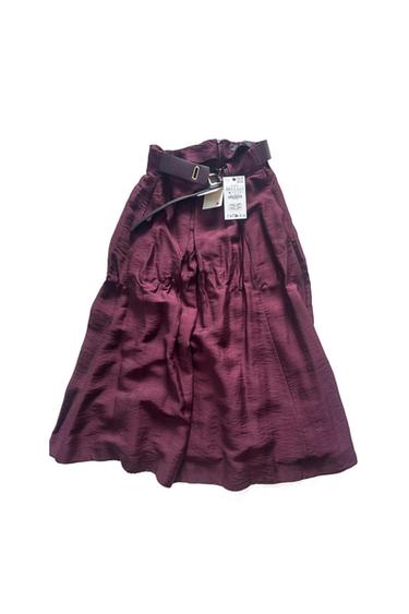 Burgundy textured midi skirt with pleats and a matching buckled belt, on a white background.