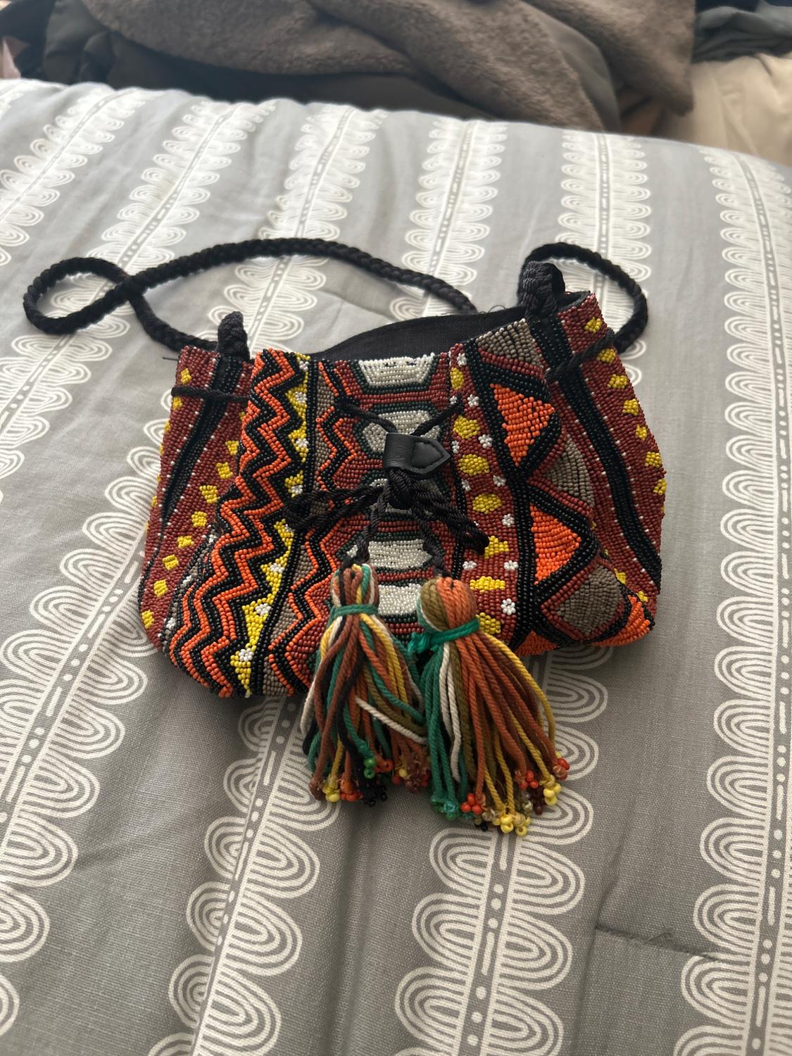 Bag with ethnic design of beads and colourful tassels on a grey background.