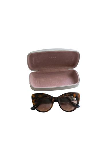 Tortoiseshell sunglasses and an open case with a pink interior. ZARA text on the case and ZARA ATELIER on the lens.