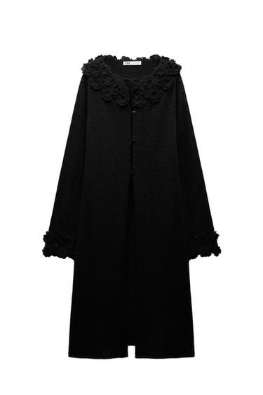 Front view of a black coat with floral lace collar and cuffs