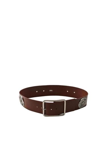 Brown belt with a silver-toned square buckle and round metal studs on the sides. ZARA text on the inside. On a white background.