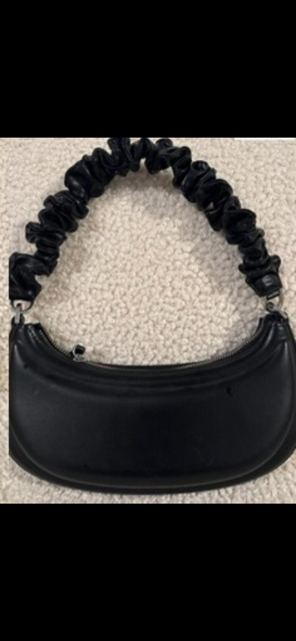 Black bag with gathered handle on a light background. Compact and modern design, ideal for complementing a casual look.