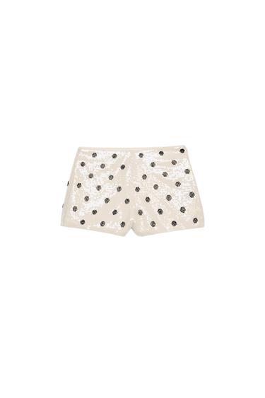 Front view of white shorts with sequins and black polka dots, mid-rise and concealed side zip.