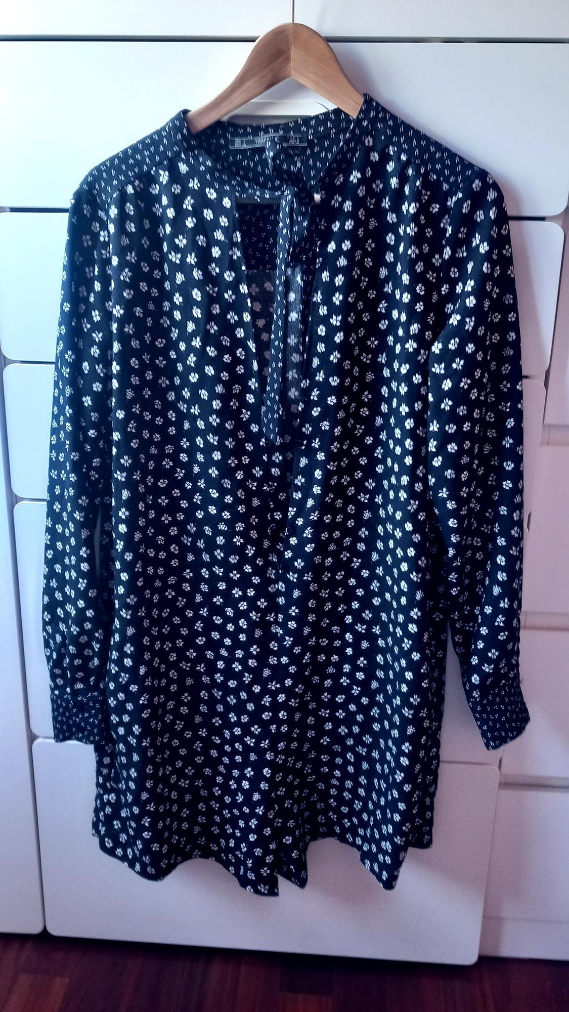 Front view of a blue blouse with a white floral print and a V-neck.