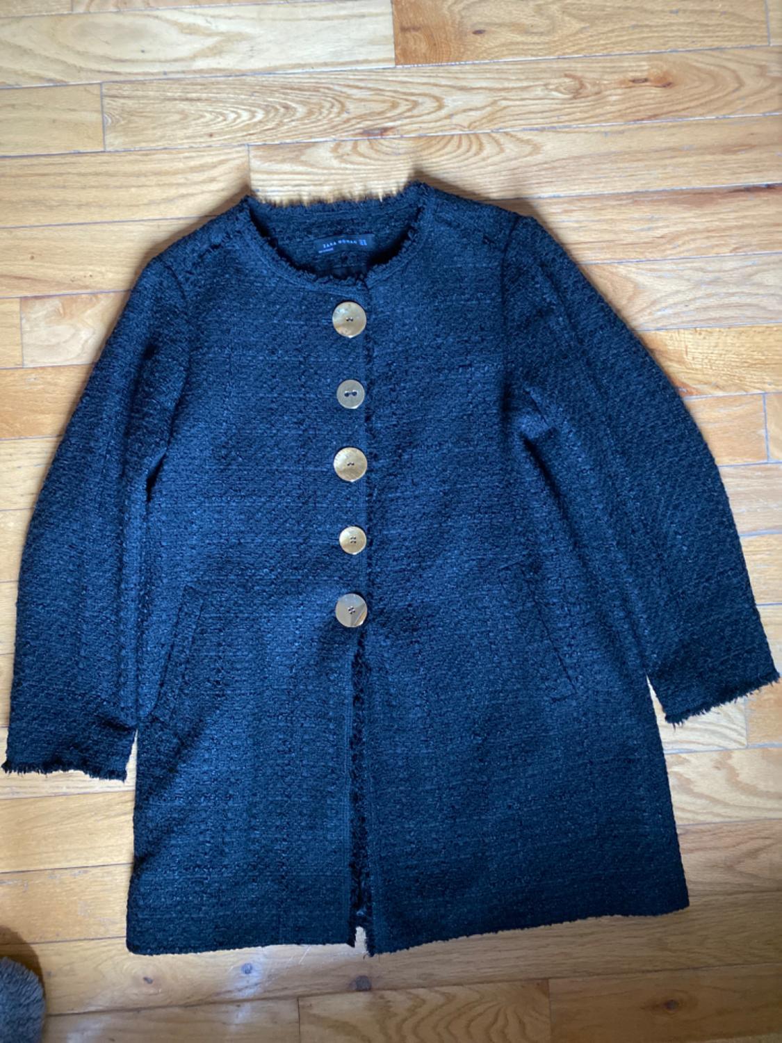 Front view of a black jacket with large buttons and side pockets.