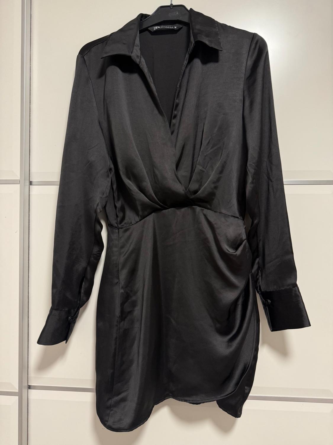 Black satin dress with a classic collar and long sleeves, hanging on a hanger against a white background.