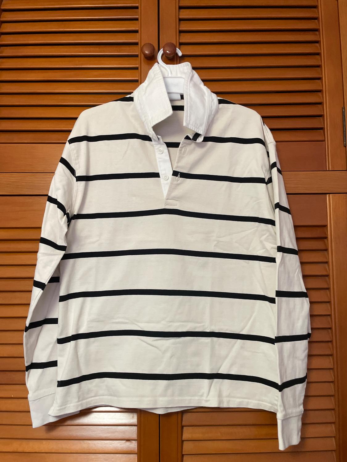 Black and white horizontal striped shirt hanging on a hanger in front of a wooden door with blinds.