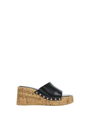 Platform sandal with cork sole and black studded upper, on a white background.