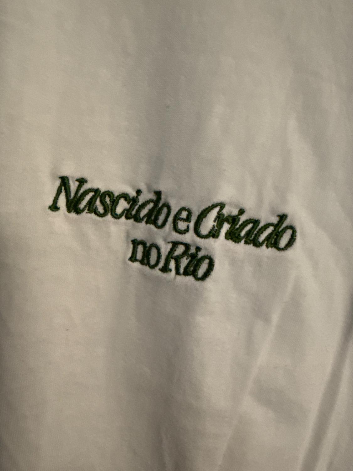 White T-shirt with green embroidered text that reads "Born and Raised in Rio".