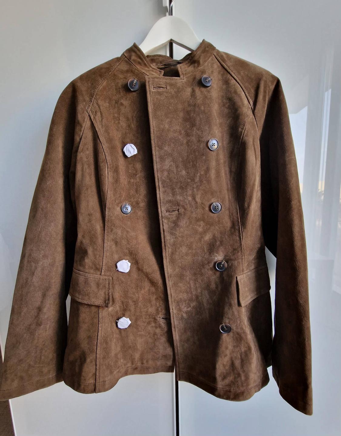 Brown double-breasted suede jacket with dark buttons, hanging on a white hanger. Some buttons have white protective paper on them.