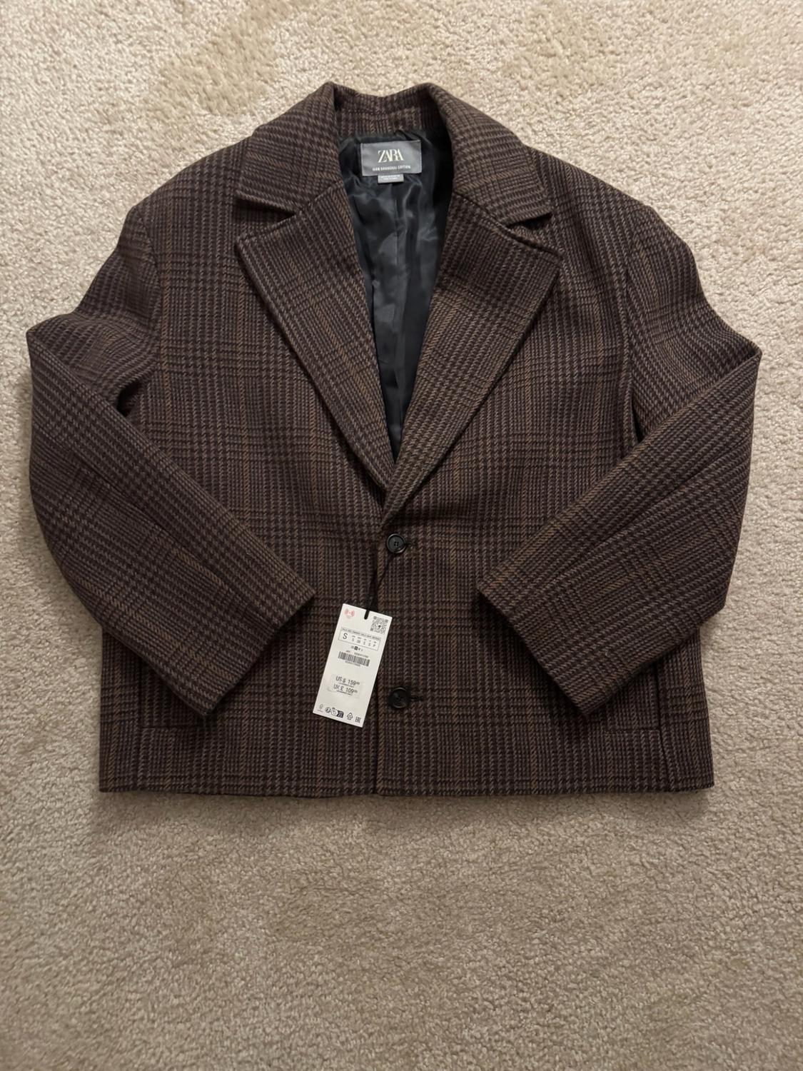 Brown plaid jacket with buttons on a beige rug. Tags with the text ZARA, S, US $ 159, UK £ 109.
