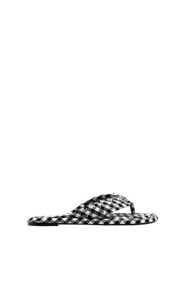 Flat toe-post sandals with a black and white check print and silver studs on the straps, on a white background.